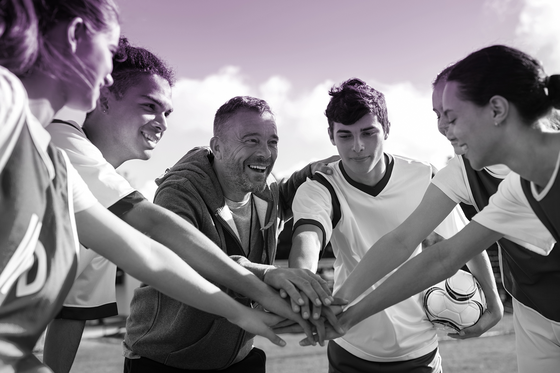 Youth athletes huddle with coach before a play